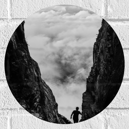 WallClassics - Muursticker Cirkel - Man tussen Rotsen boven Wolken in Zwart-wit - 30x30 cm Foto op Muursticker