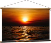 WallClassics - Textielposter - Zwemmende Mensen in Zee bij Ondergaande Zon - 90x60 cm Foto op Textiel
