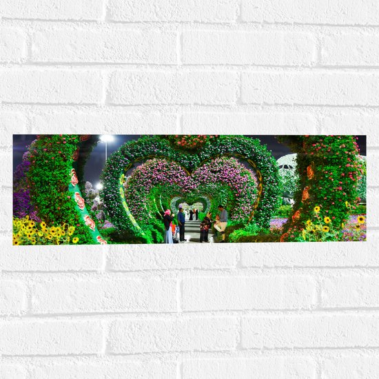 WallClassics - Muursticker - Hartvormige Bloemenbogen in Park - 60x20 cm Foto op Muursticker