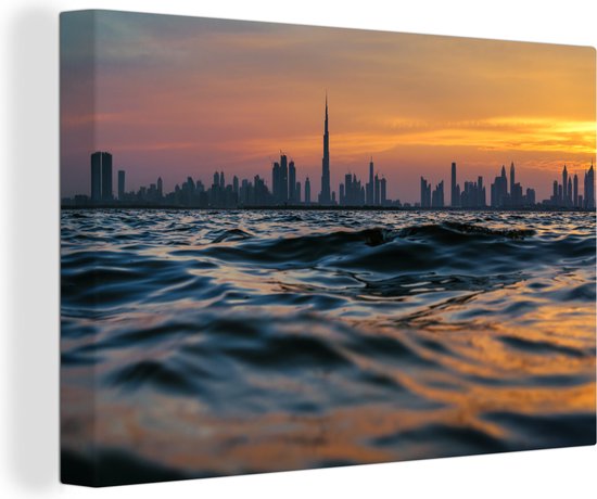 Canvas Schilderij Een schitterende foto van Dubai vanaf het water bij zonsondergang - 120x80 cm - Wanddecoratie