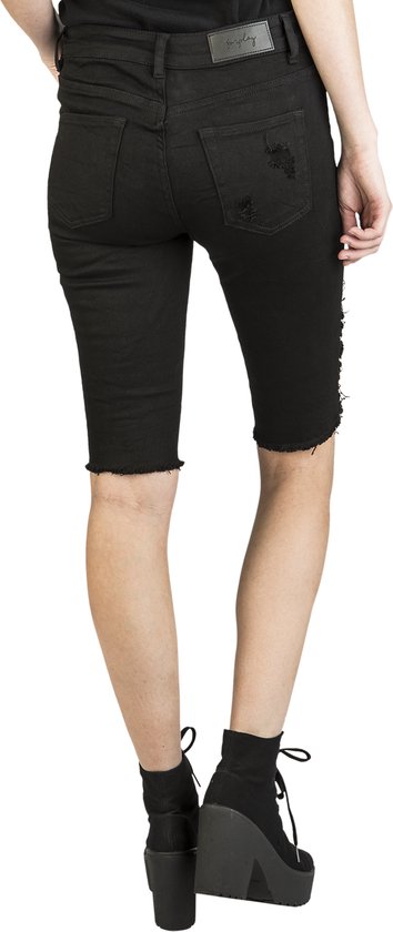Achterkant van een vrouw in zwarte denim bermudashorts met rafelige zoom en lichte scheuren.
