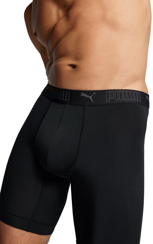 Close-up van de voorkant van een man die zwarte boxer briefs draagt met een Puma-logo op de tailleband.