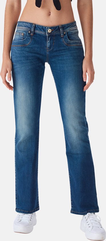 Een model draagt een blauwe bootcut jeans met sierlijke stiksels op de zakken.
