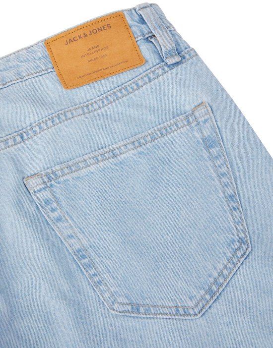 Sluiting van een lichtblauwe spijkerbroek met een bruin leren label van Jack & Jones.