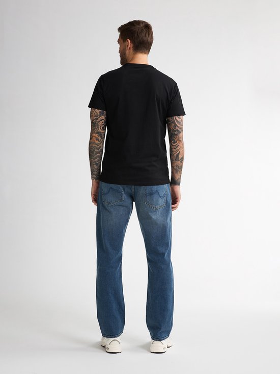 Man met tatoeages, achterkant van zwarte t-shirt en blauwe jeans.