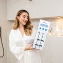Vrouw met een witte badjas die een zwart 2-laags doucherek vasthoudt.