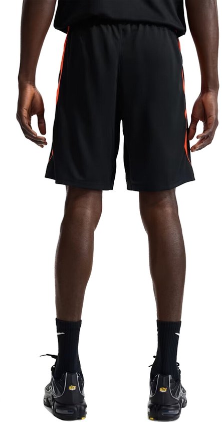 Zij- en achterkant van een zwarte Nike voetbalshort met oranje accenten.