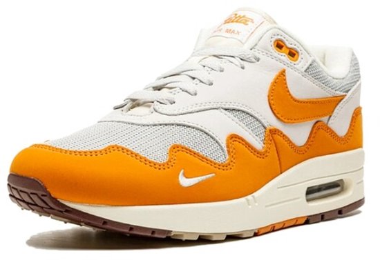 Voorkant-zijzicht van een witte en oranje Nike Air Max 1 Patta sneaker met beige zool en bruine details.