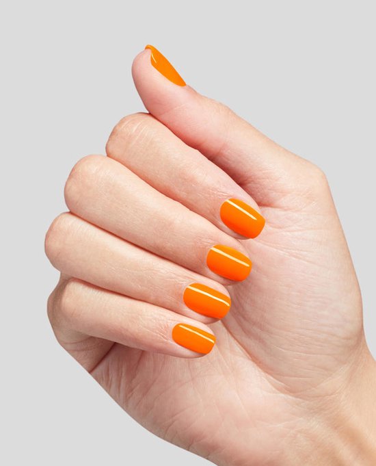 Hand met nagels gelakt in een glanzende, heldere oranje kleur tegen een grijze achtergrond.