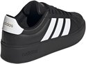 Zwarte damessneaker met dikke zool, witte Adidas-strepen op de zijkant en gouden details.