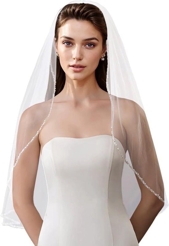 La mariée porte une robe blanche bustier et un voile aux bords décorés de perles et de cristaux.