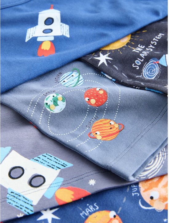 Een close-up van gestapelde hemdjes met prints van planeten, de zon, sterren en raketten.