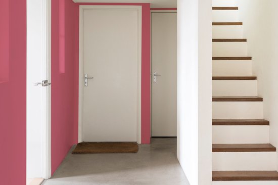 Een hal met een roze muur, witte deuren en een trap met houten treden.