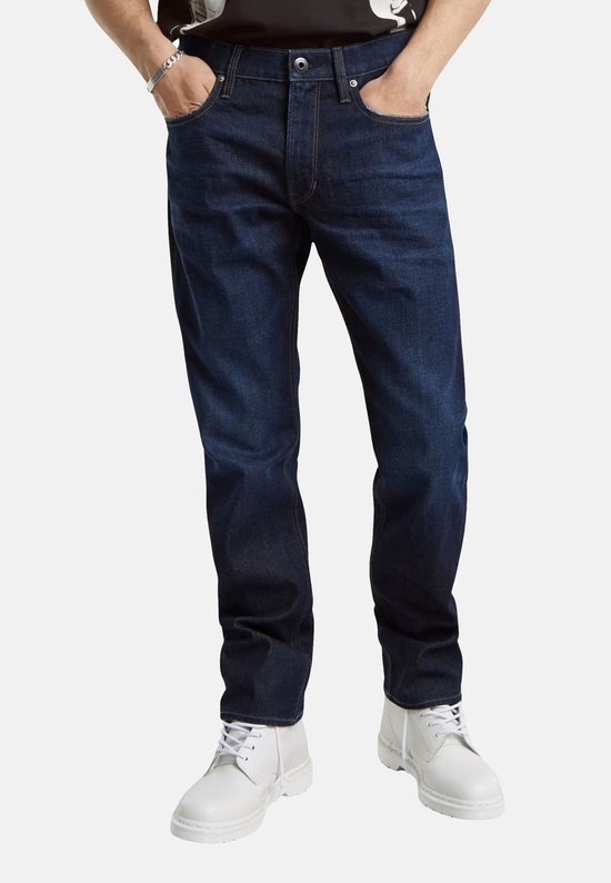 Man met donkerblauwe G-Star Mosa Straight jeans en witte laarzen.