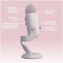 Witte microfoon met labels voor drie capsules, microfoon gain, opnamepatronen, interne schokdemper, microfoondemping en koptelefoonvolume.