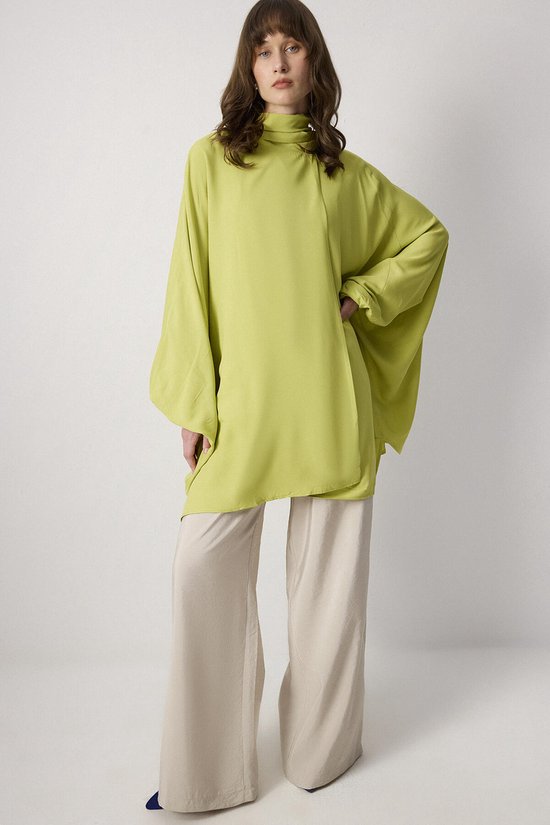 Lichtgroene kimono met wijde mouwen en hoge kraag, gedragen op een beige broek.