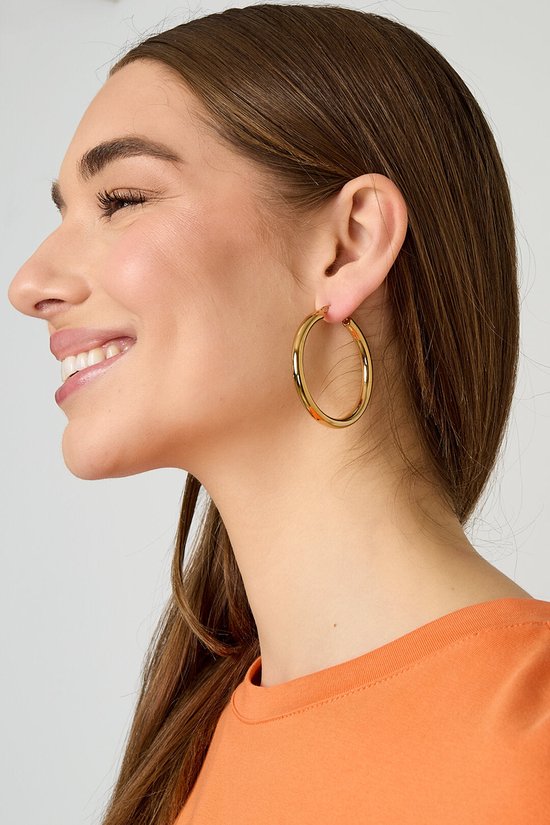 Model met gouden oorringen, glimlachend.