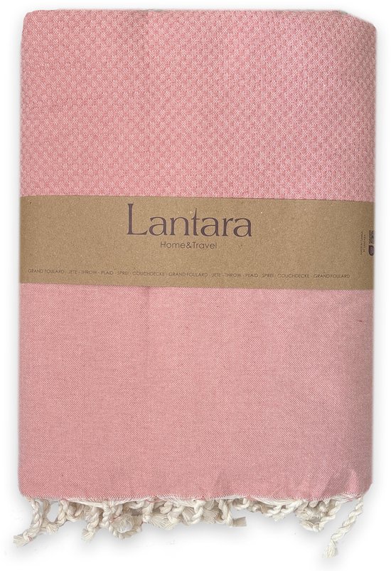 Lichtroze wafel plaid met witte franjes en een kartonnen band met 'Lantara Home & Travel'.