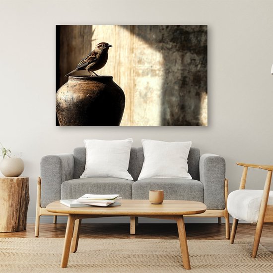 Een bruine vogel op een pot, hangend aan een muur boven een grijze bank in een woonkamer.