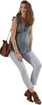Zwangere vrouw in grijze blouse met goudkleurige stippen en ruches, lichtblauwe jeans, bruine enkellaarsjes en bruine tas.