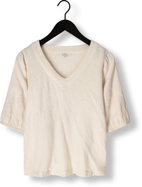 Ecru blouse met V-hals, kapmouwtjes en geborduurde details op de mouwen, hangend aan een kledinghanger.