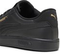Close-up van de hiel van een zwarte sneaker met gouden Puma-logo's.