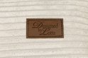 Lederen label met 'Designed by Lotte' op een lichte crèmekleurige ribstof hondenmand.
