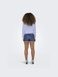 Achterkant van een vrouw in blauwgestreepte blouse en denim shorts met opgerolde zoom.