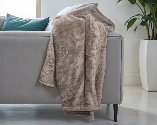 Bruine teddy plaid op een grijze bank met groene en blauwe kussens.