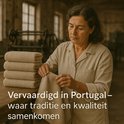 Une femme inspecte des serviettes couleur sable, 'Fabriqué au Portugal'.