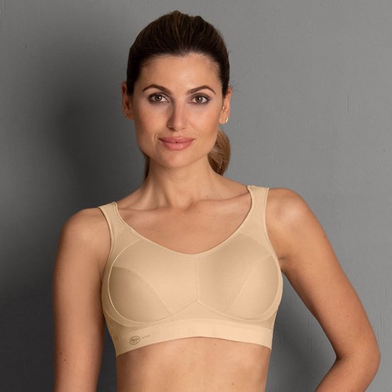 Vrouw draagt een beige sportbeha met gedetailleerde naden en comfortabele bandjes.