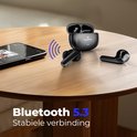 Zwarte draadloze oordopjes en oplaadcase op een houten tafel naast een smartphone, met Bluetooth 5.3-logo.