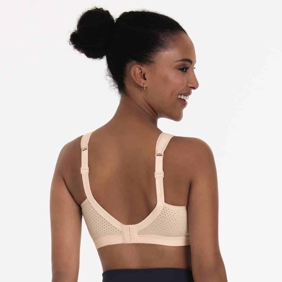 Model van achteren gezien in een beige sportbeha zonder beugel met geperforeerd materiaal.