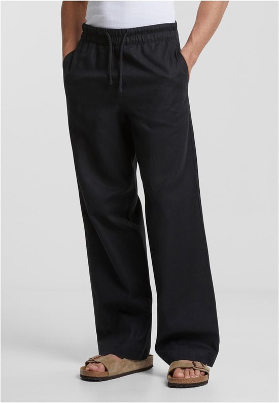 Model in een loszittende, zwarte katoenen linnen broek met rechte pijpen en een trekkoord.