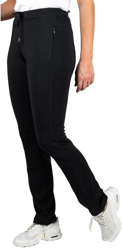 Vrouw in zwarte trainingsbroek en rode sporttop met witte accenten, staand.