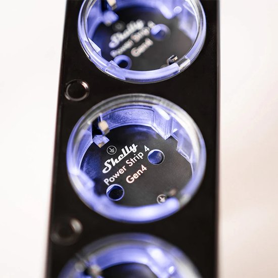 Close-up van een Shelly Power Strip 4 Gen4 stopcontact met blauwe LED-verlichting op een zwarte behuizing.