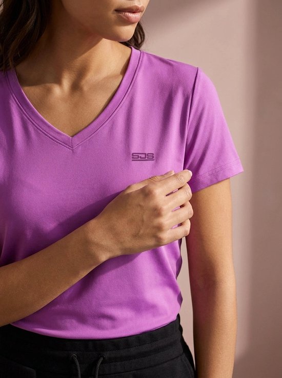 Paarse sportshirt met V-hals en SJG logo op de borst. Gedragen door een vrouw.