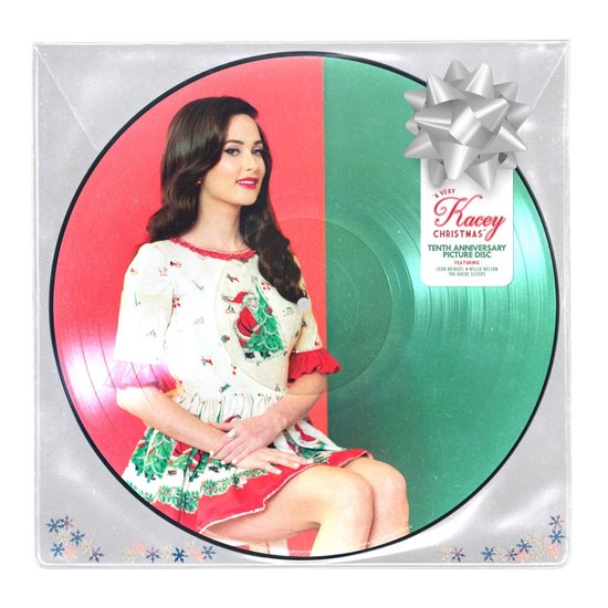 Kacey Musgraves in een kerstjurk, zittend naast een groene en rode vinylplaat met tekst.