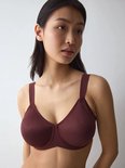 Model draagt een bordeauxrode Triumph minimizer-bh met voorgevormde cups en een subtiel geweven patroon.