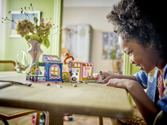 Enfant jouant avec le magasin de vêtements vintage LEGO Friends sur une table.