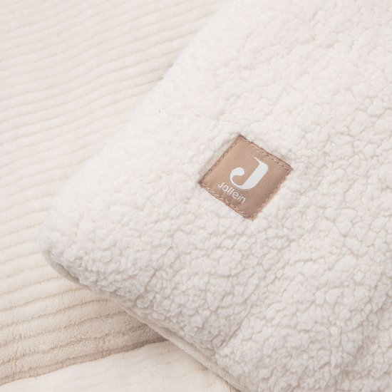 Close-up van een beige boxkleed met teddy textuur en een Jollein label, naast een ribbelig gedeelte.