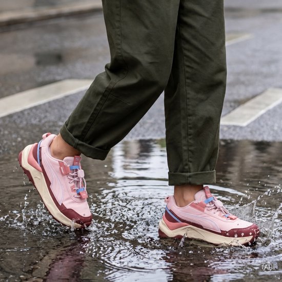 Roze Puma Evolve 2.0 trail-sneakers met donkerrode accenten en een beige zool, gedragen in een waterplas.
