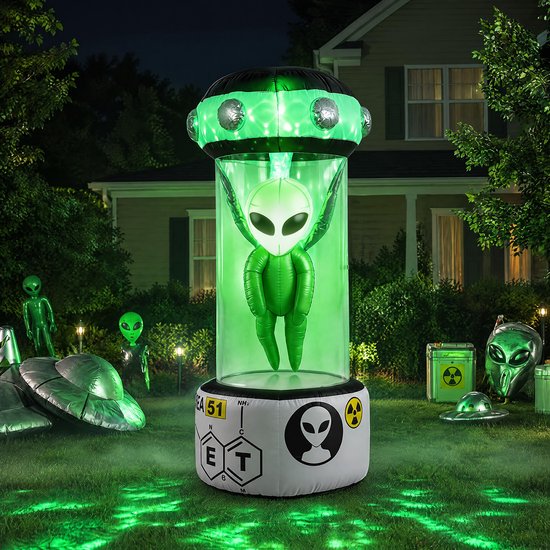 Opblaasbare alien in ruimtecapsule in een tuin met Halloween-versieringen en andere alien-objecten.