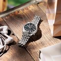 Zilveren Citizen Tsuyosa horloge met zwarte wijzerplaat en stalen horlogeband op een houten tafel.