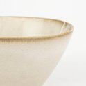 Detailopname van een beige stenen kom met een karakteristieke bruine rand.