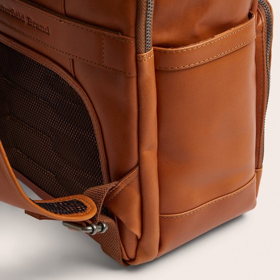 Zijkant van bruine lederen rugzak met 'The Chesterfield Brand' logo, zijvak en ademend mesh paneel.