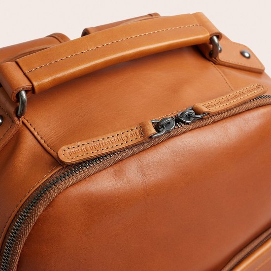 Bovenzijde van bruine lederen rugzak met handvat en ritsen met 'The Chesterfield Brand' merknaam.
