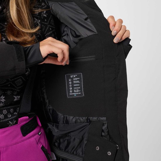 Vrouw opent een binnenzak van haar zwarte ski-jas, met technische informatie erop.