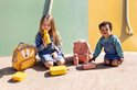 Twee kinderen met Trixie rugzakken, drinkflessen en snackdoosjes in de vorm van dieren in geel en roze tinten.