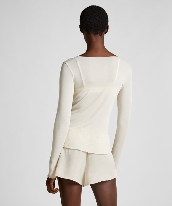 Achterkant van model met kort haar in een beige shirt met lange mouwen en een korte broek.